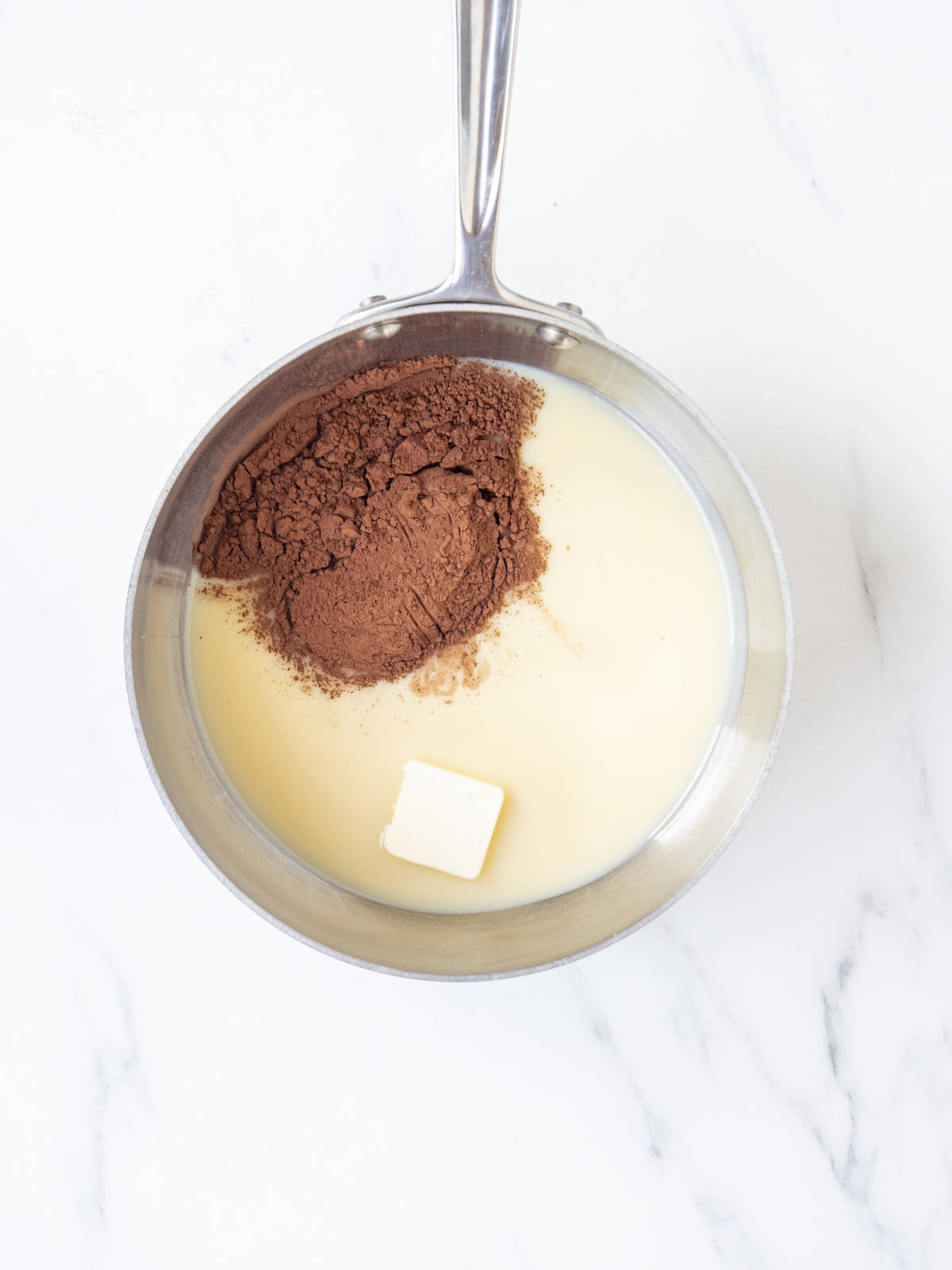 A saucepan with condensed milk, butter and cocoa powder.
