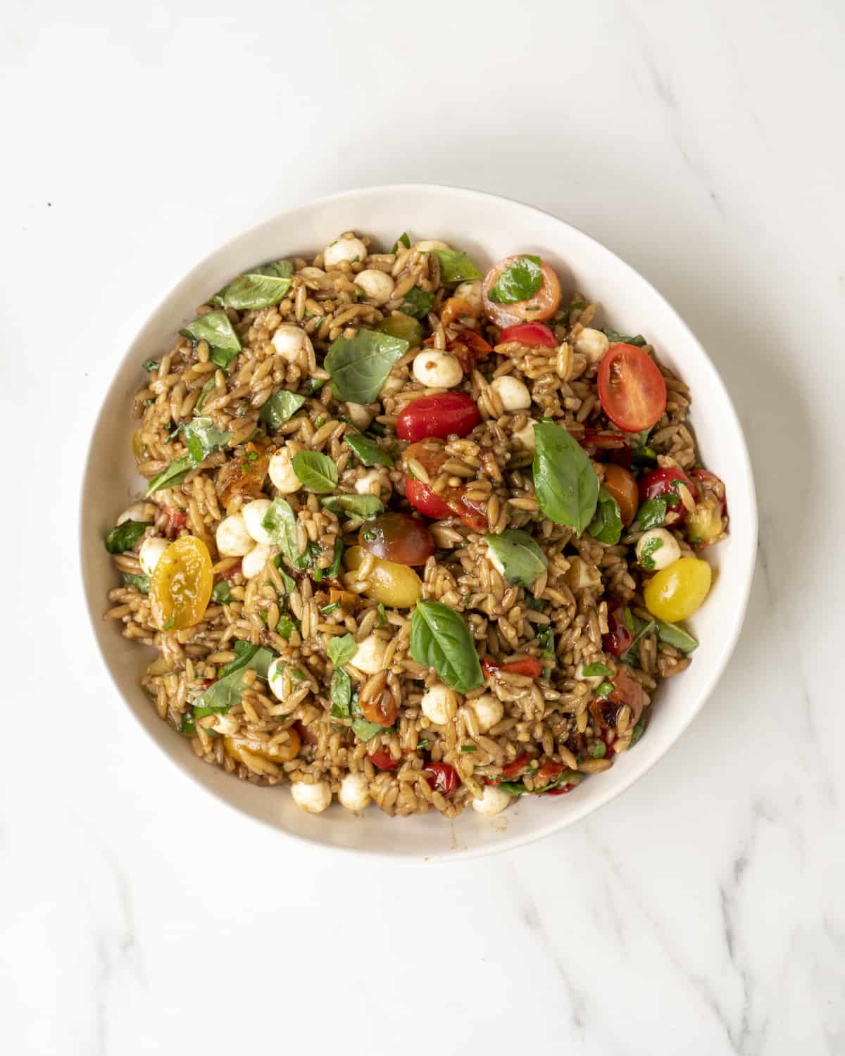 Large white mixing bowl with caprese orzo salad.