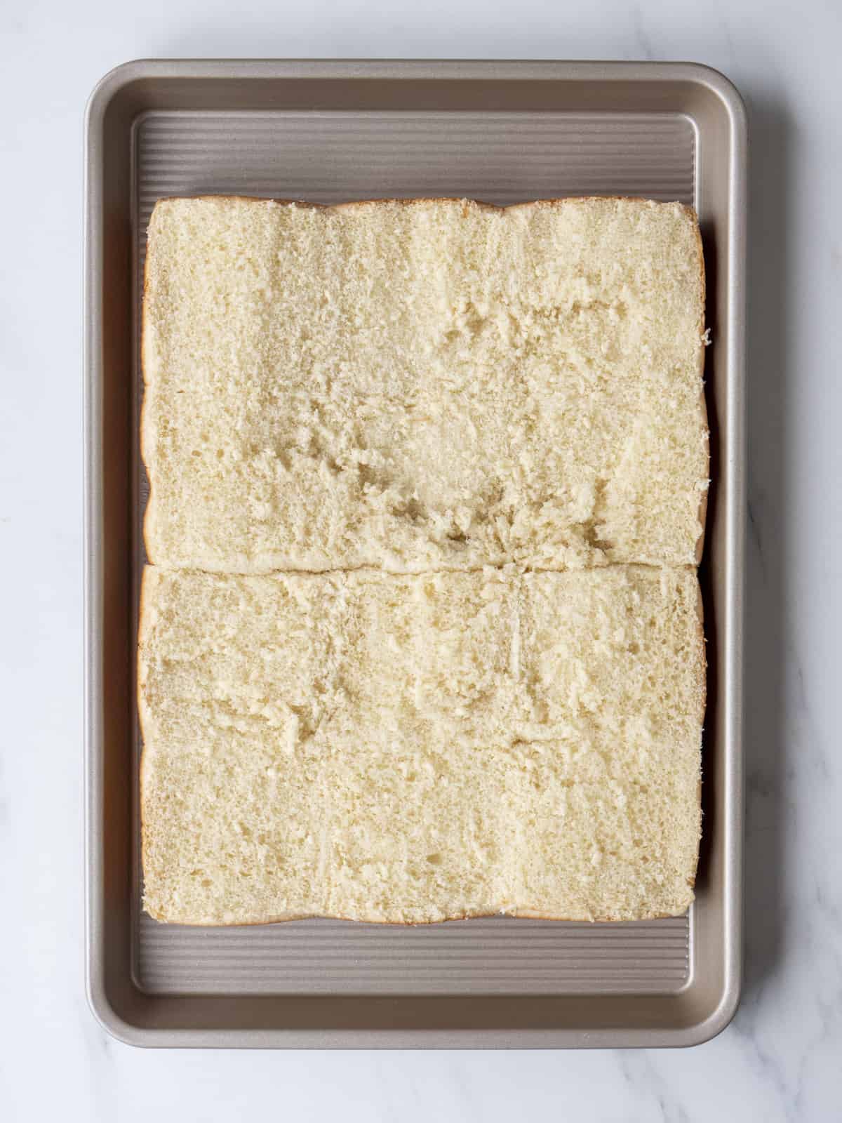 A baking sheet with a 3x4 grid of bottom half of slider buns.
