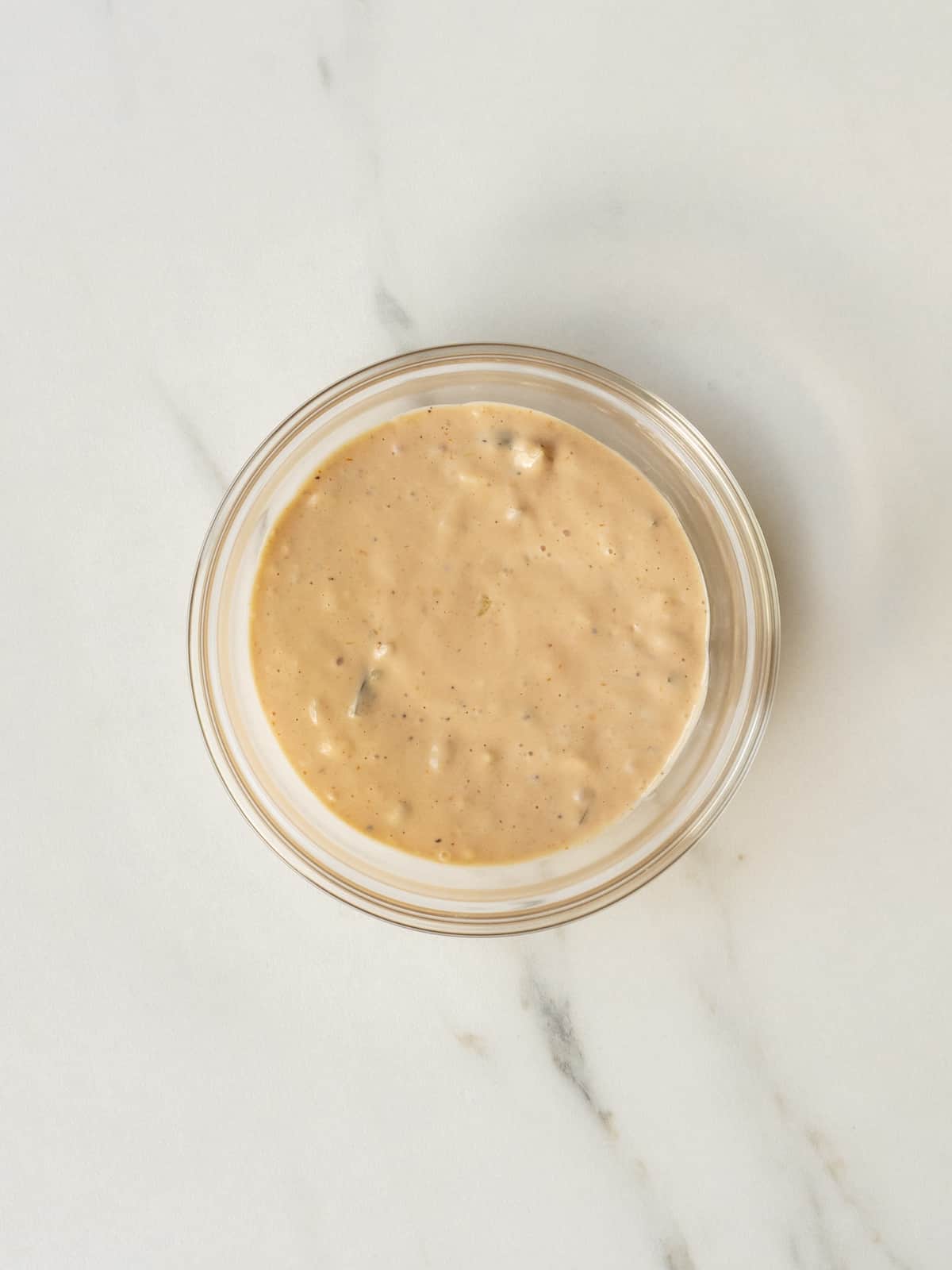 A small glass mixing bowl with special sauce made of mayonnaise, ketchup and sweet relish whisked together.