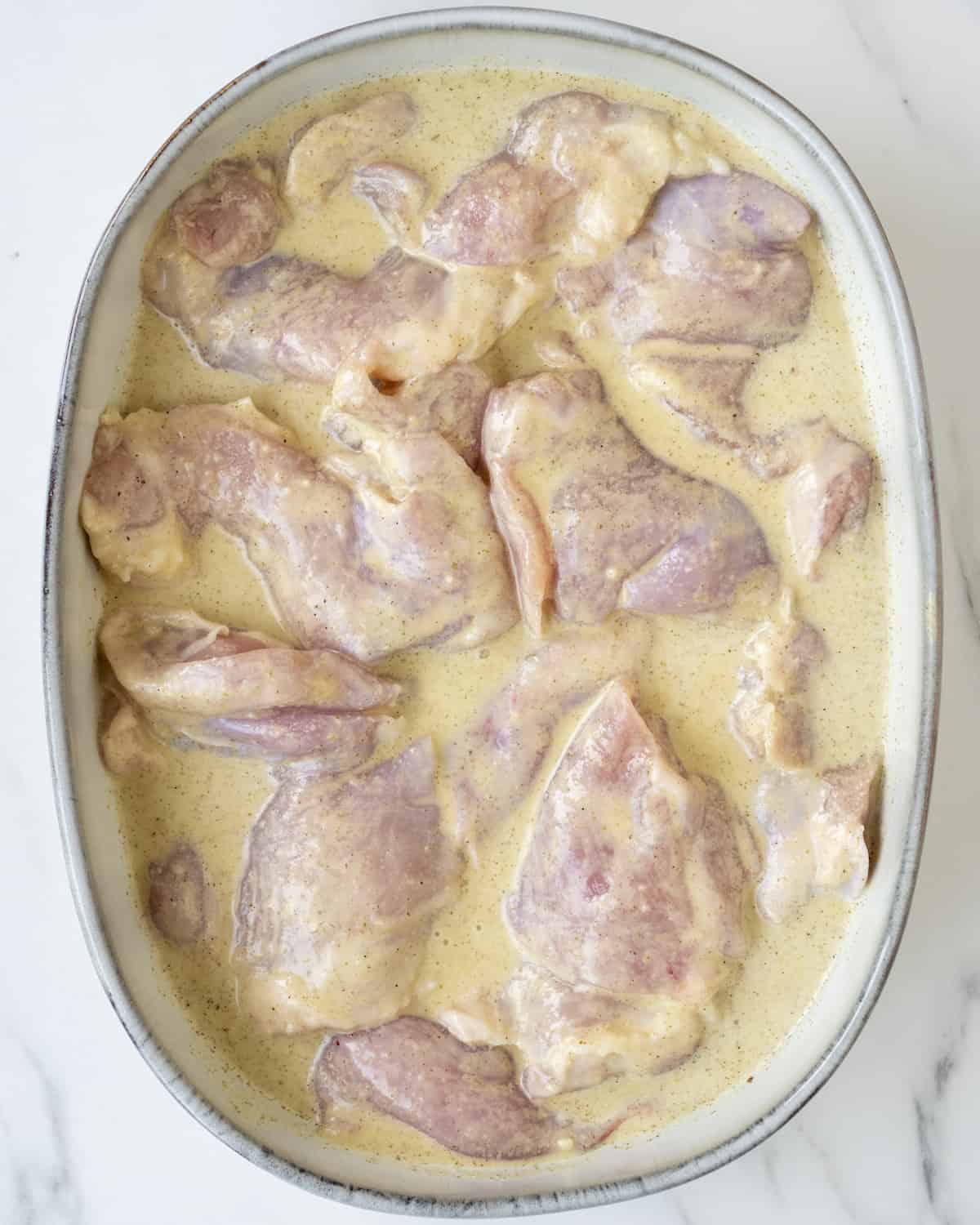 The chicken is sitting in a large dish with the blended marinade.  