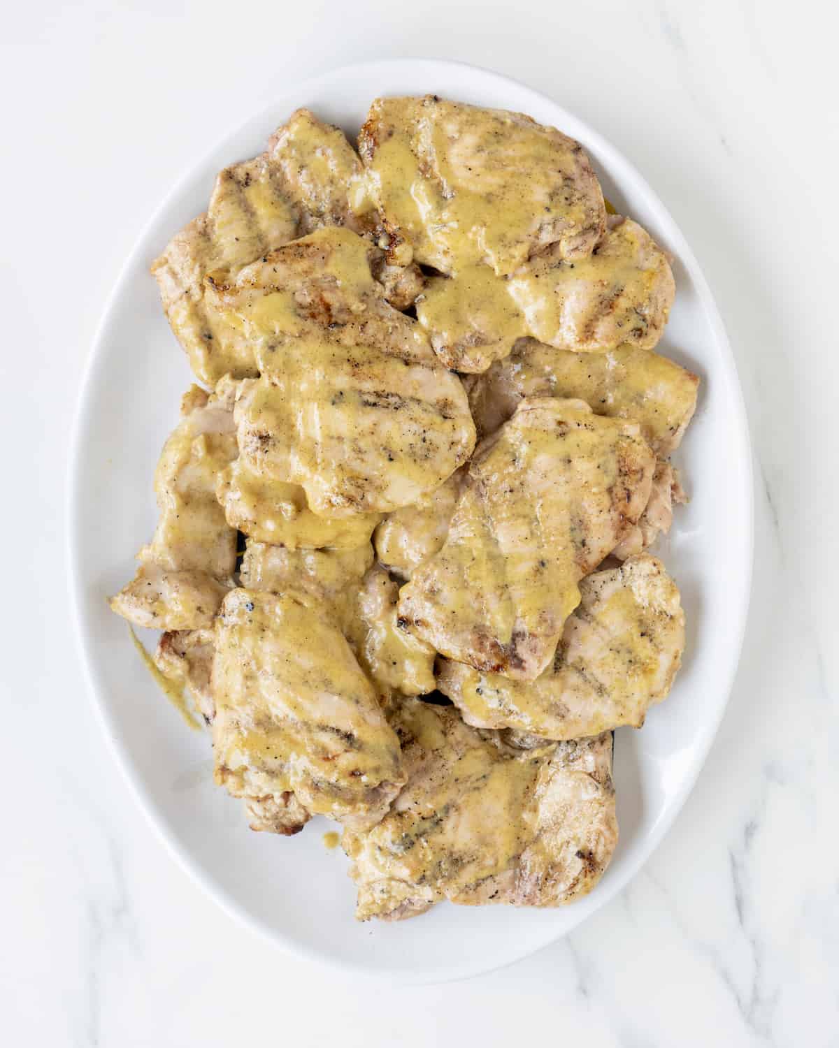 Many pieces of grilled chicken covered in the Mojo sauce are sitting on a plate.  