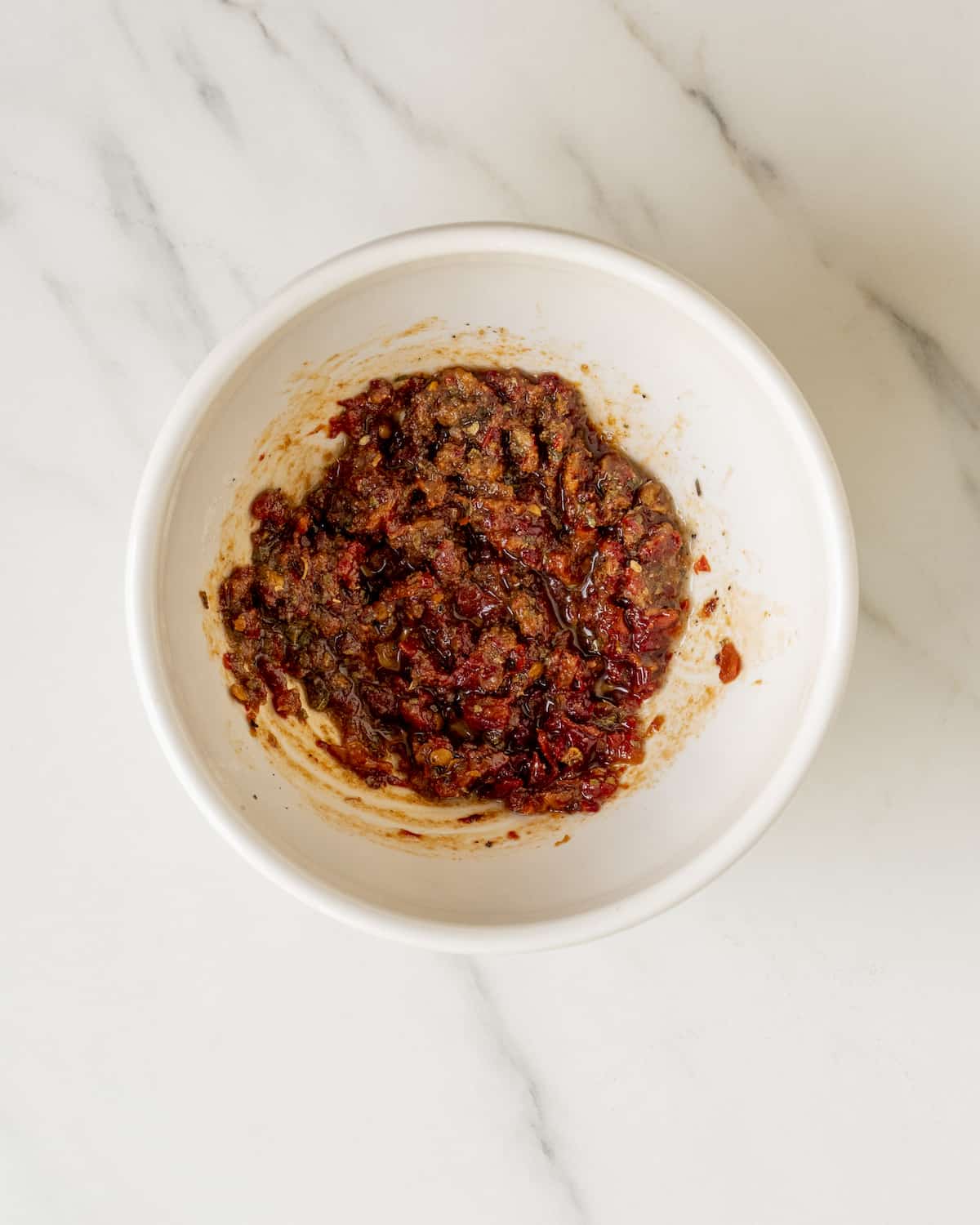 Vegetable oil, chopped chipotle peppers in adobo, garlic powder, cumin, dried oregano, and black pepper mixed together in a small bowl.