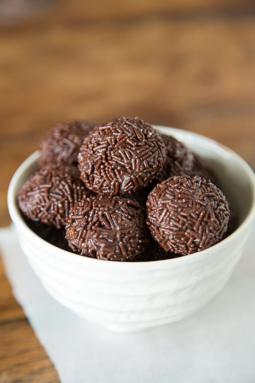Brigadeiro - A Brazilian Chocolate Bonbon that will rock your world A white bowl of Brigadeiro, a Brazilian Chocolate Bonbon coated in chocolate sprkinles with the background blurred out.