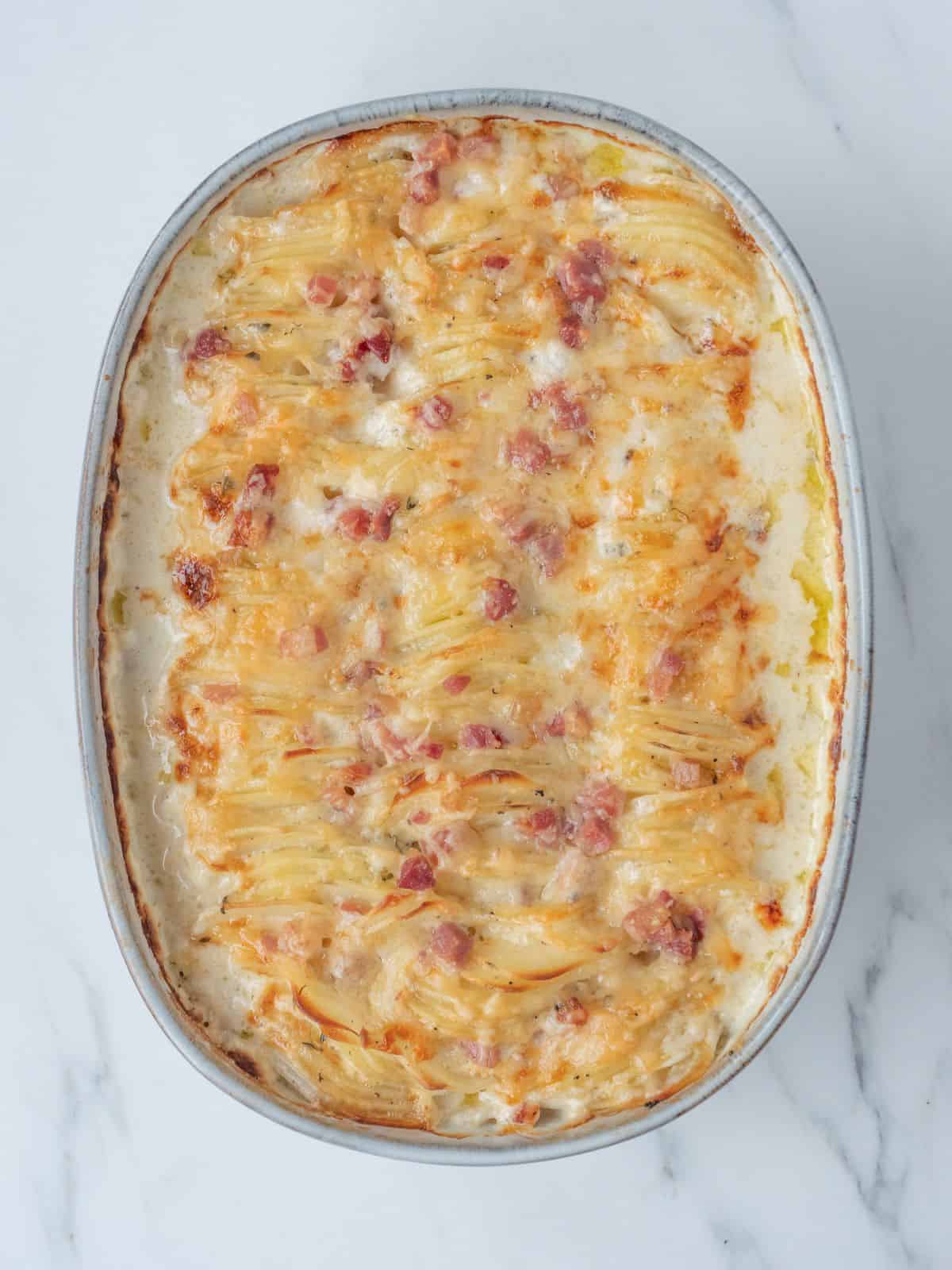 An oval baking dish with hasselback scalloped potatoes baked.