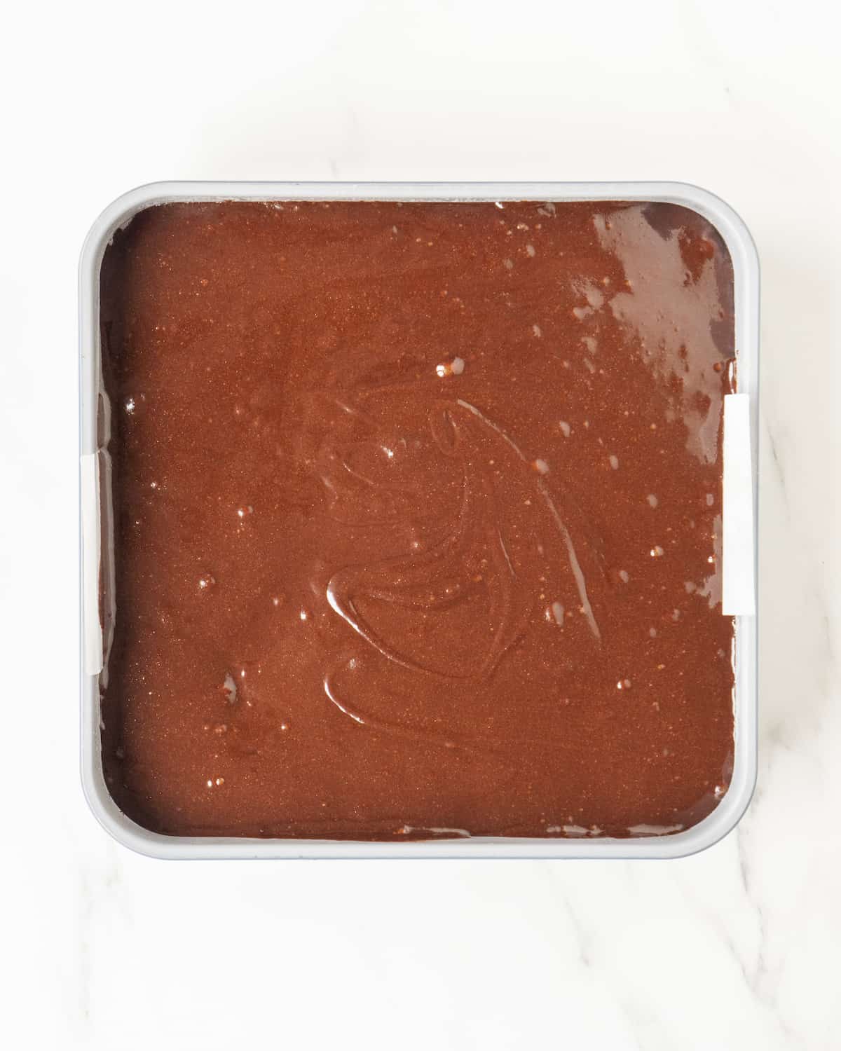 A layer of brownie batter in a baking pan.  