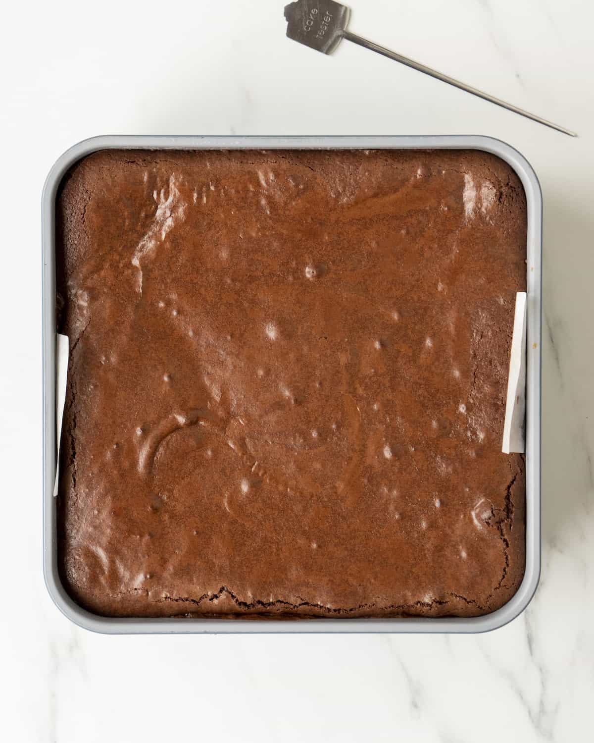 A final baked dish of slutty brownies sitting next to a tooth pick.  